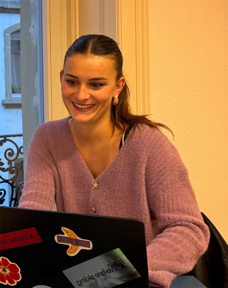 Inès, souriante, à sa table de travail.